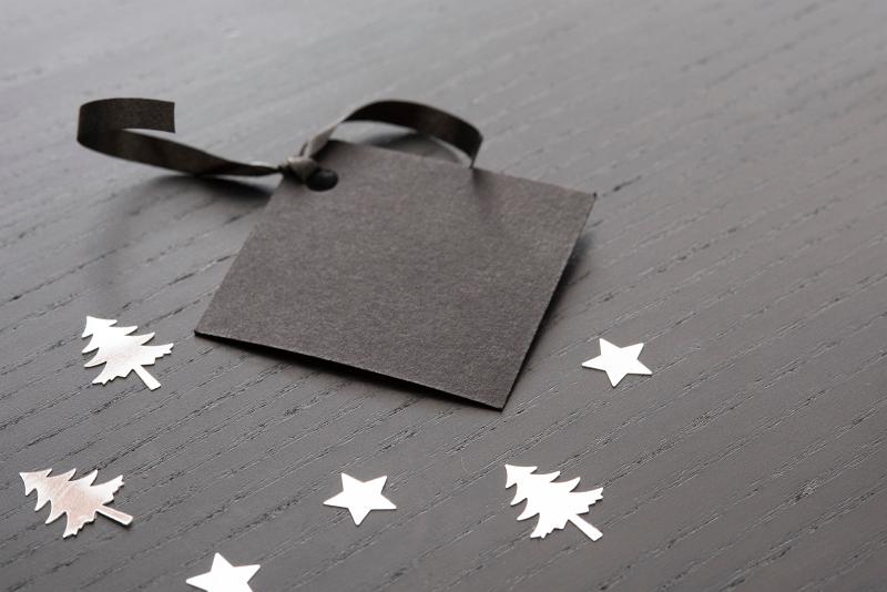 Free Stock Photo: Plain black gift tag with space for text and surrounded by silver christmas shapes
