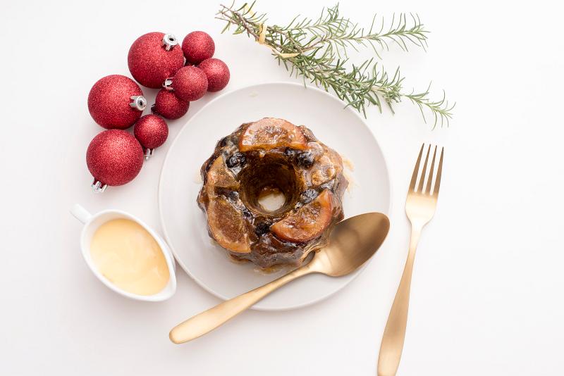 Free Stock Photo: a overhead view of a round traditional christmas fruit pudding with fruit decorations, served with sauce