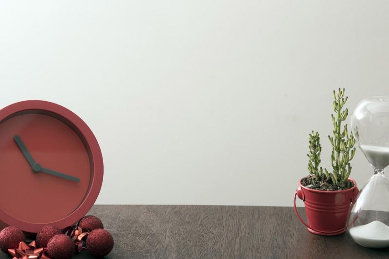 Free Stock Photo: Christmas concept of being short on time with a festive red clock surrounded by baubles and bows on a table with an hourglass and potted plant with central copy space