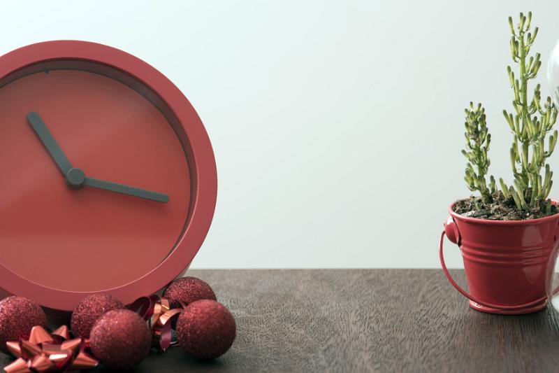 Free Stock Photo: Christmas time concept with festive red clock surrounded by matching decorations on a table with a potted plant and copy space