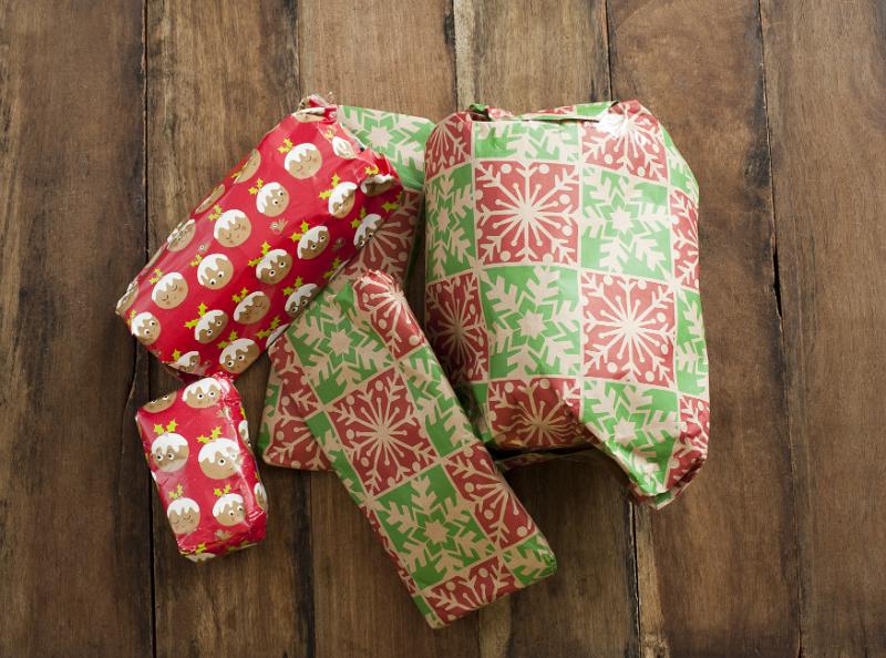 Download image of Colorful Christmas wrapping on pile of presents Free Stock Photo: Colorful Christmas wrapping on pile of presents on a wooden table viewed from above