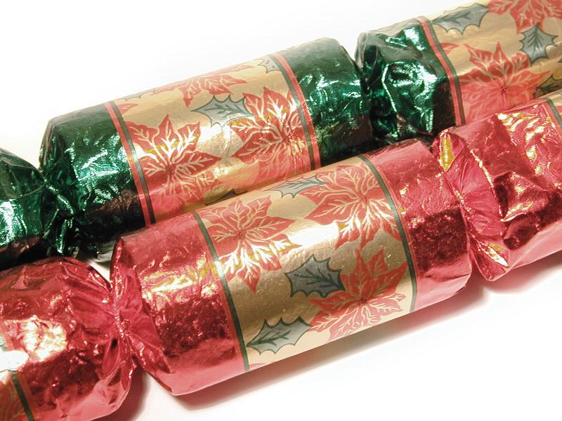 Free Stock Photo: Close Up of Two Festive Foil Wrapped Christmas Crackers with Poinsettia Patterned Paper on White Background