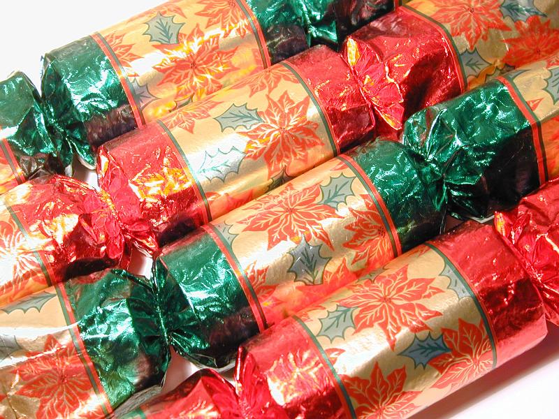 Free Stock Photo: Festive green and red Christmas crackers in foil with a pattern of Xmas poinsettia for decorating the seasonal table, close up background view
