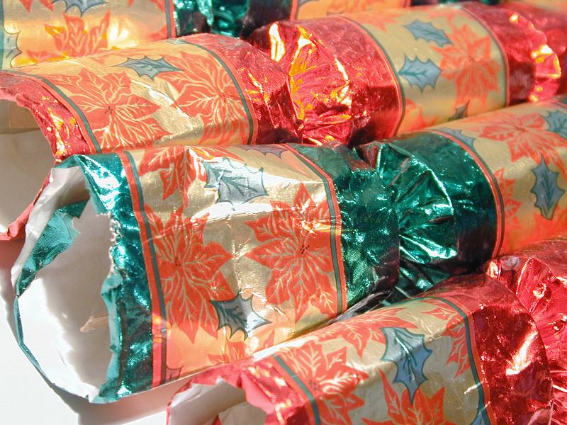 Free Stock Photo: Colorful foil Christmas crackers for decorating the table with red poinsettias on gold, close up detail