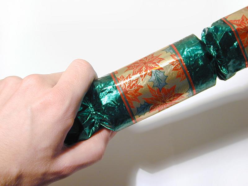 Free Stock Photo: Close Up of Hand Pulling Christmas Cracker Open Over White Background