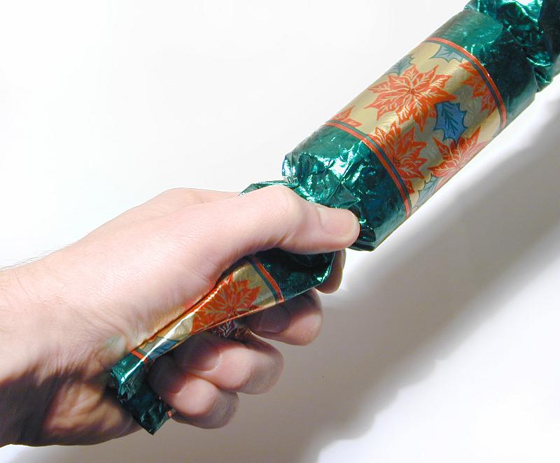 Free Stock Photo: Man pulling a colorful Christmas cracker with a friend during a festive celebration to see who wins the treat inside, closeup of his hand over white