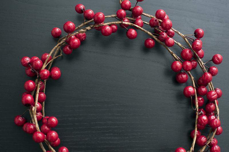 Free Stock Photo: Christmas wreath of colourful red cranberries over a dark wood background with central copy space for a seasonal greeting