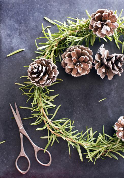 Free Stock Photo: Making homemade Christmas decorations with scissors alongside a half completed pine wreath with cones viewed from above