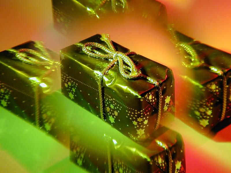 Free Stock Photo: A small wrapped christmas gift lit by coloured lights with a mesmerising lens effect