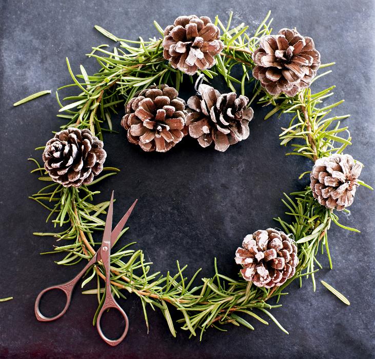 Free Stock Photo: Rustic handmade Christmas wreath of natural pine foliage and cones over a dark textured background with a pair of scissors