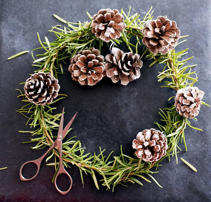 Download image of Rustic handmade Christmas wreath of natural pine Free Stock Photo: Rustic handmade Christmas wreath of natural pine foliage and cones over a dark textured background with a pair of scissors