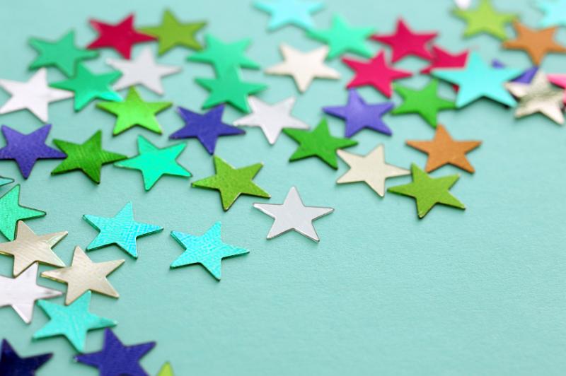 Free Stock Photo: Background Image of Colorful Metallic Star Shaped Stickers Scattered on Light Blue Background with Copy Space