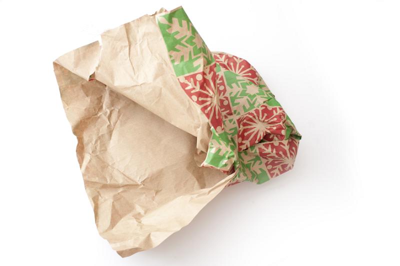 Free Stock Photo: Torn crumpled Christmas wrapping paper from an opened gift on white with copy space