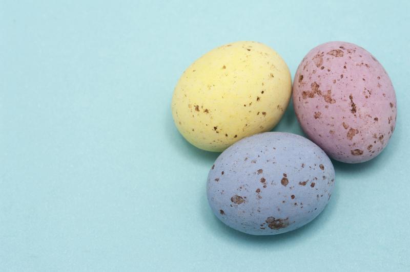 Free Stock Photo: Three pastel coloured speckled candy Easter Eggs on blue with copyspace.