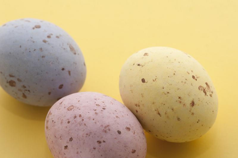 Free Stock Photo: Speckled Candy Easter Eggs in pastel shades of pink, blue and yellow on a yellow background.