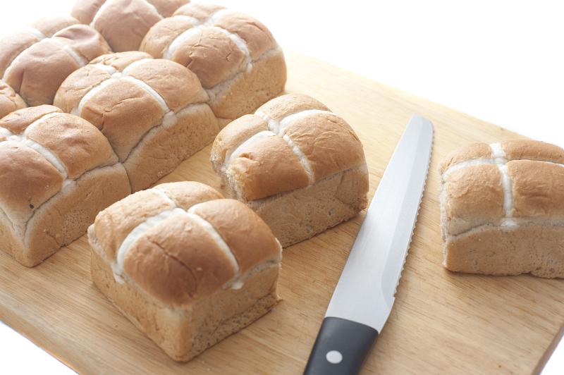 Free Stock Photo: A batch of freshly baked hot cross buns separated on a wooden board with a knife.