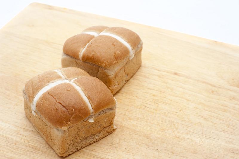 Free Stock Photo: Two fresh glazed Hot Cross Buns on a wooden cutting board with copyspace