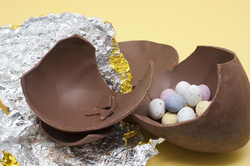 Free Stock Photo: Large chocolate Easter egg broken in to pieces on the foil wrapper and filled with small speckled candy eggs.