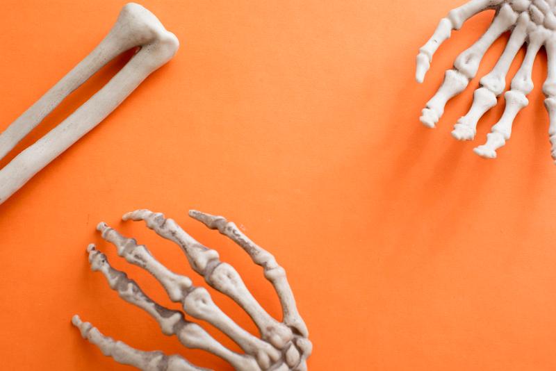 Free Stock Photo: halloween flat lay composed of skeleton bones on and orange surface with copyspace in the centre