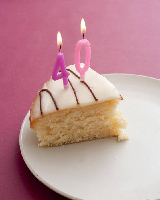 Free Stock Photo: Slice of Vanilla Cake Decorated with White Icing and Chocolate Drizzle on White Plate with 40th Birthday Candles Burning on Pink Background