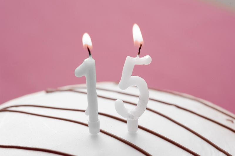 Free Stock Photo: Fifteenth birthday party with burning number 15 candles on an iced cake over a pink feminine background with copyspace