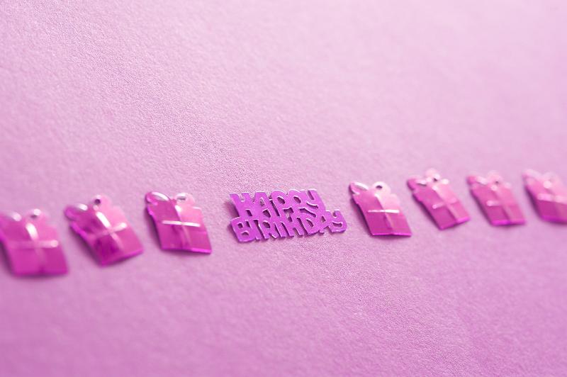 Free Stock Photo: Fuchsia Gift Shaped Foil Confetti in a Line Framing Happy Birthday Message on Pink Background