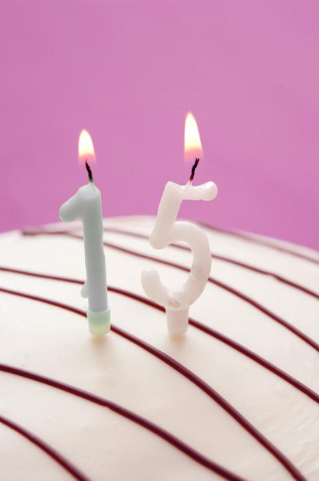 Free Stock Photo: Decorative numeric burning candles for 15th birthday on top of the icing of a glazed birthday cake over a pink background