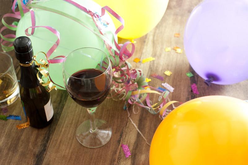 Free Stock Photo: Over View of Birthday Balloons, Streamers and Confetti with Bottle and Glass of Red Wine Still Life