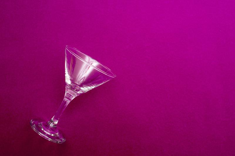 Free Stock Photo: Empty martini cocktail glass lying on its side in the corner on a maroon background with copy space for your festive party greeting or invitation