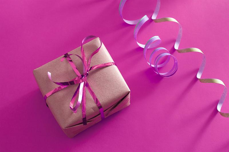 Free Stock Photo: Birthday gift for a girl with a gift wrapped box tied with a pink ribbon and streamer over a pink background, high angle view