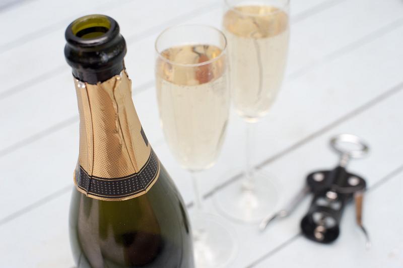 Free Stock Photo: Bottle of luxury champagne with blank gold labeling for celebrating a festive event or holiday, close up high angle view with two full flutes of champagne and a bottle opener behind