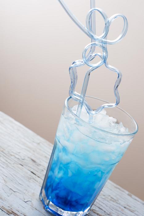Free Stock Photo: Party ice drink with blue syrup and curved cocktail glass straw in close-up on white wooden table
