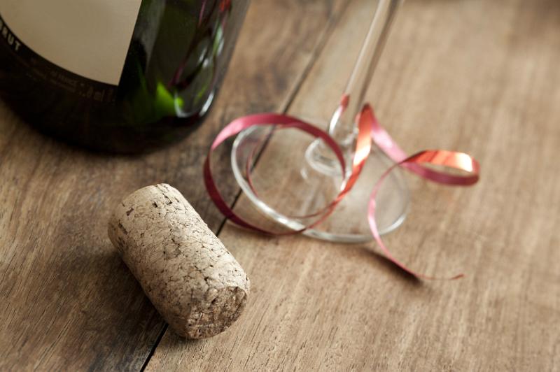Free Stock Photo: Party drinks concept with bottle of bubbly or champagne alongside an opened cork and glass tied with festive red ribbon