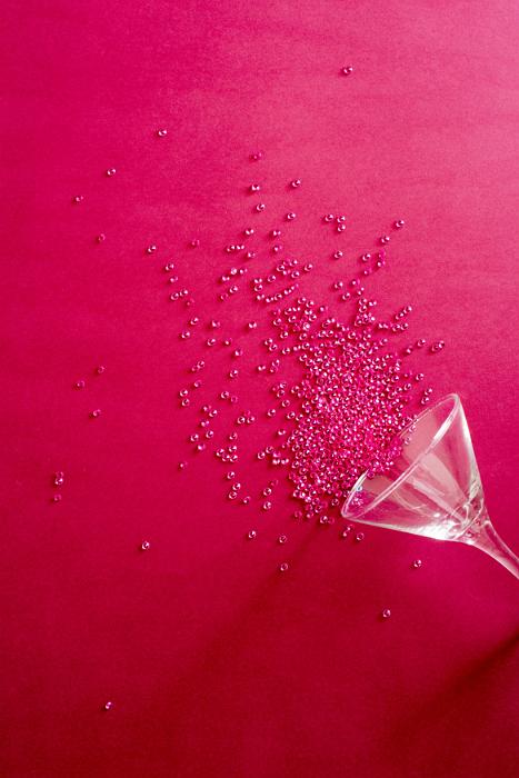 Free Stock Photo: Festive red party background with upended cocktail glass spilling sparkling red beads onto a matching background with copy space