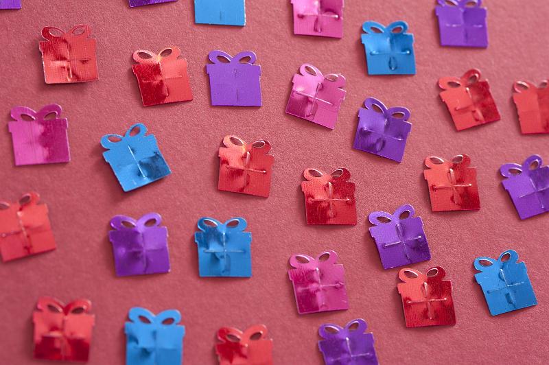 Free Stock Photo: Multi-Colored Gift Shaped Foil Birthday Confetti Scattered on Red Background
