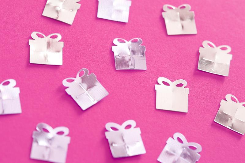 Free Stock Photo: Silver Birthday Confetti Shaped Like Wrapped Presents Scattered on Hot Pink Background
