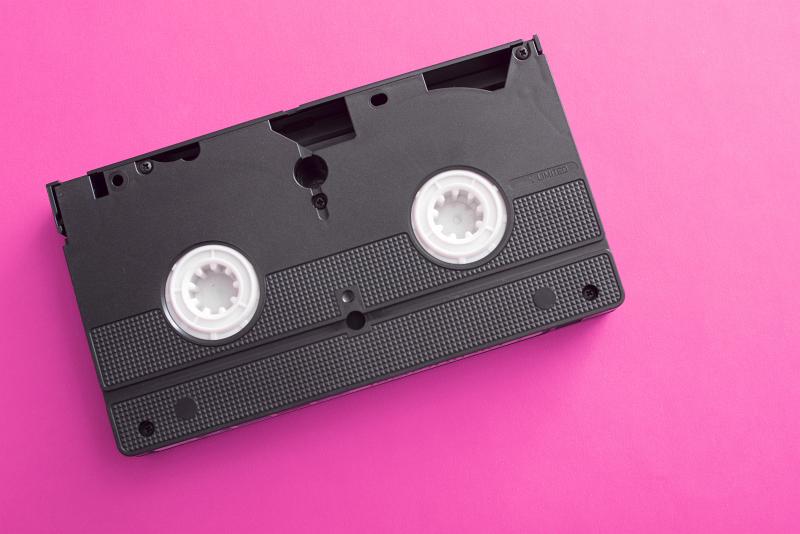 Free Stock Photo: X-rated movie concept with an old unlabelled video cassette lying on a bright pink background with copy space viewed from above