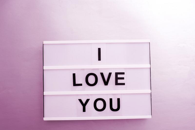 Free Stock Photo: White lightbox with I Love You message sign of black changeable letters, against wall in purple lighting. Love concept