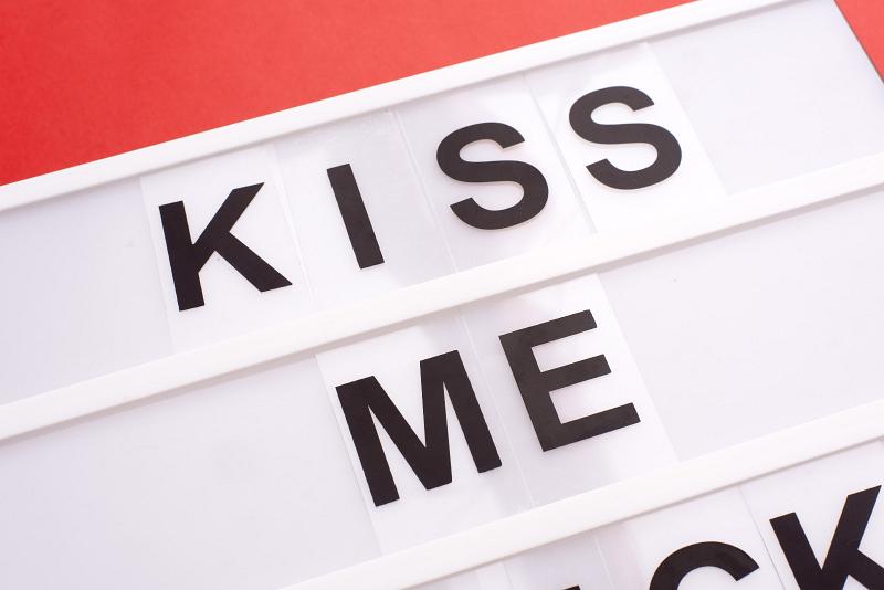 Free Stock Photo: Close-up cropped image of white lightbox with black changeable sign Kiss Me, on red background. Love message concept