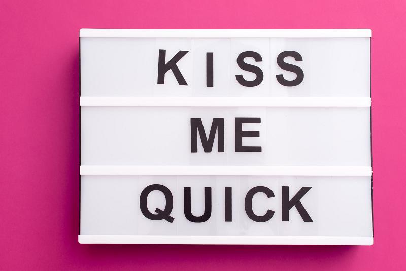 Free Stock Photo: Kiss Me Quick message on white lightbox with black changeable letters, close-up over pink background