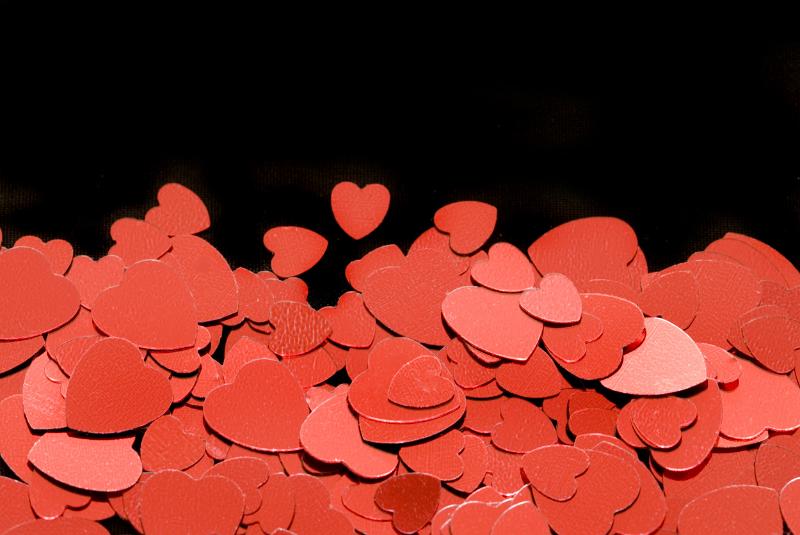 Free Stock Photo: a background or bottom border of red metallic heart shapes on a black backdrop