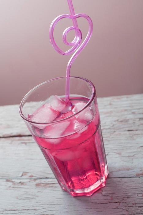 Free Stock Photo: Close-up glass of red cocktail with ice cubes and curved heart-shaped pink straw, over old painted wooden surface