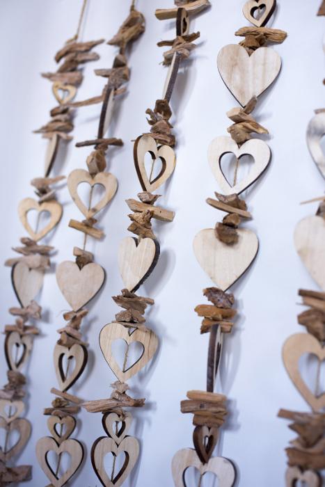 Free Stock Photo: Unpainted wooden hearts strung on beading strings decoration hanging close to white wall. Close-up background concept