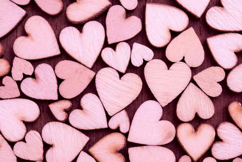 Free Stock Photo: Background pattern of pink wooden hearts in three sizes arranged randomly on red in a concept of love, romance, anniversary, wedding or Valentines Day