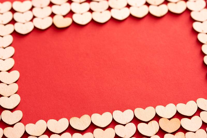 Free Stock Photo: Festive hearts frame for Valentines Day with a triple row of white wooden heart shapes arranged on a red background with copy space