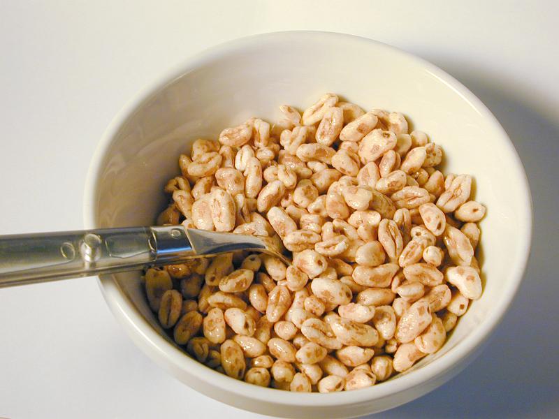 Free Stock Photo: High angle view of commercial puffed wheat breakfast cereal in a white ceramic bowl with a spoon