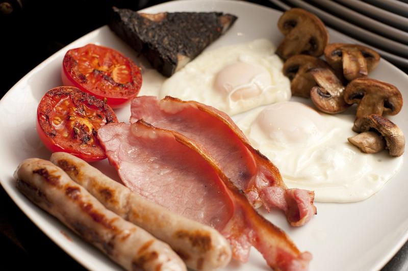 Free Stock Photo: Wholesome cooked English breakfast with fried eggs, grilled bacon, sausages, mushrooms, plack pudding and tomato for a hearty diet