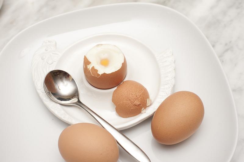 Free Stock Photo: Boiled eggs for breakfast with a soft boiled egg in an egg cup served with two additional eggs on the side