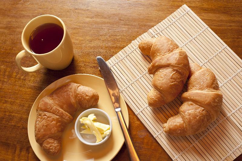 Free Stock Photo: View from above of a typical French breakfast with freshly baked flaky croissants with a pat of butter and a mug of strong black filter coffee