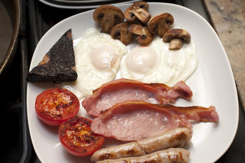 Free Stock Photo: Full cooked English breakfast with fried eggs, bacon, sausages, mushrooms, tomato and black pudding served on a plate for a hearty meal